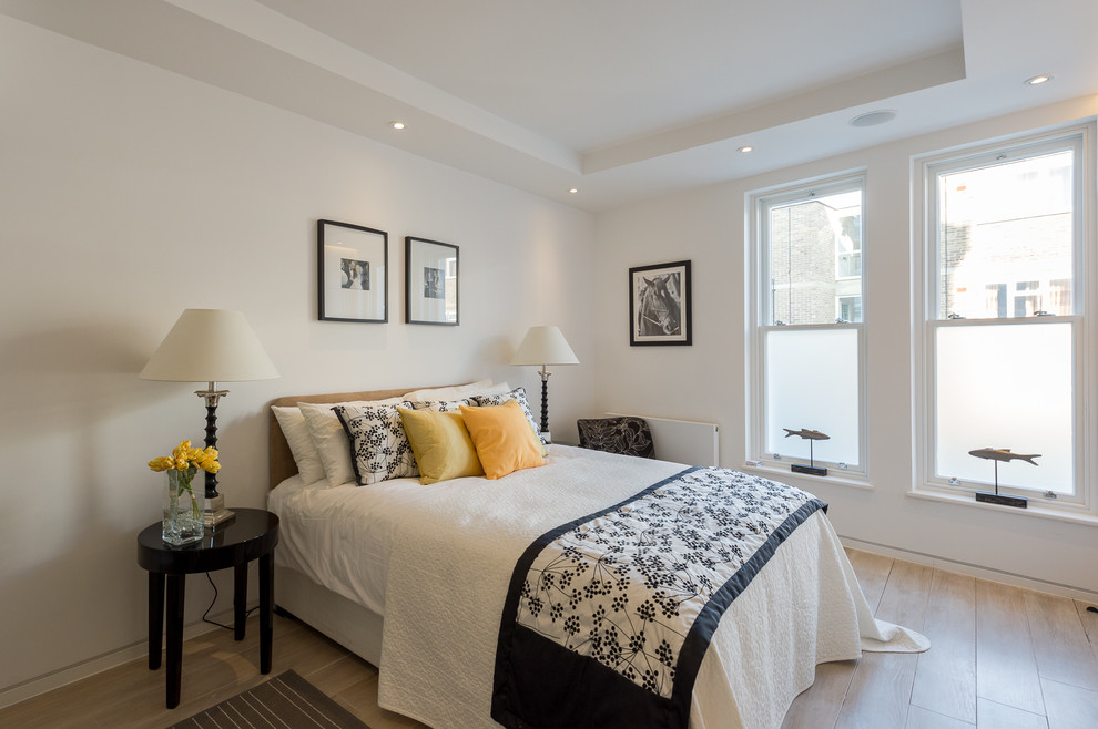 Design ideas for a mid-sized transitional bedroom in London with white walls and light hardwood floors.