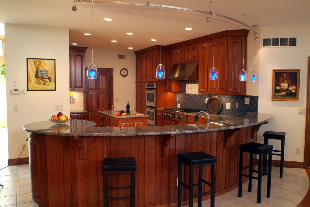 Example of a large transitional u-shaped ceramic tile eat-in kitchen design with an undermount sink, raised-panel cabinets, medium tone wood cabinets, granite countertops, blue backsplash, ceramic backsplash, stainless steel appliances and an island