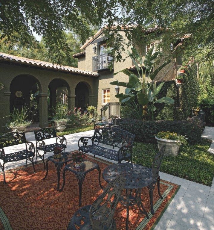 Large mediterranean two-storey stucco green house exterior in Orlando with a shingle roof.