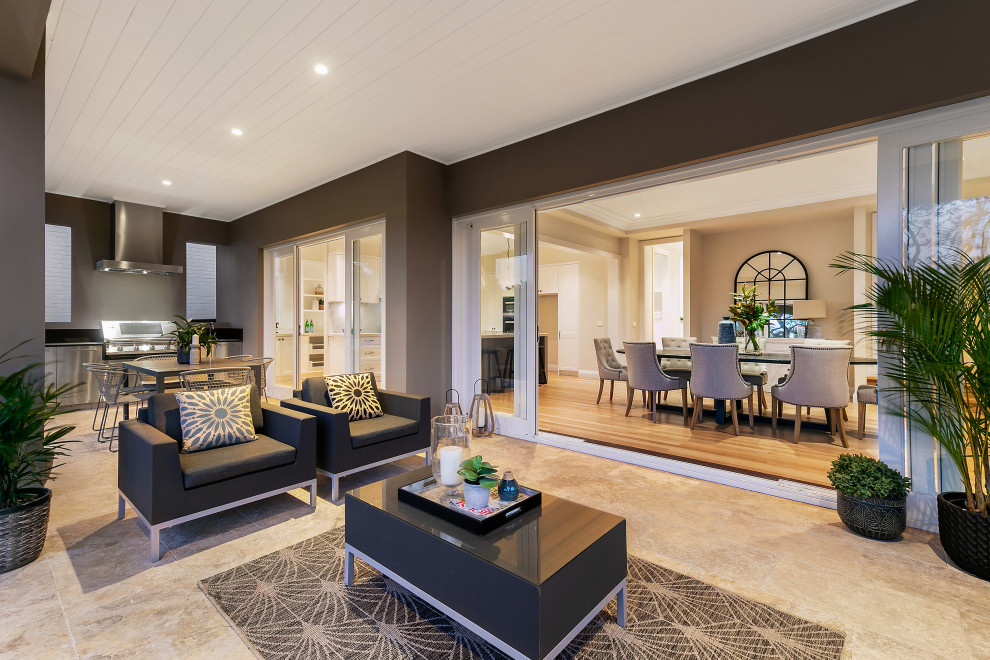 This is an example of a mid-sized transitional backyard verandah in Sydney with an outdoor kitchen, natural stone pavers and a roof extension.