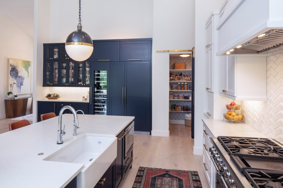 Eat-in kitchen - large transitional u-shaped light wood floor and beige floor eat-in kitchen idea in Austin with a farmhouse sink, recessed-panel cabinets, white cabinets, quartzite countertops, white backsplash, ceramic backsplash, paneled appliances, an island and white countertops