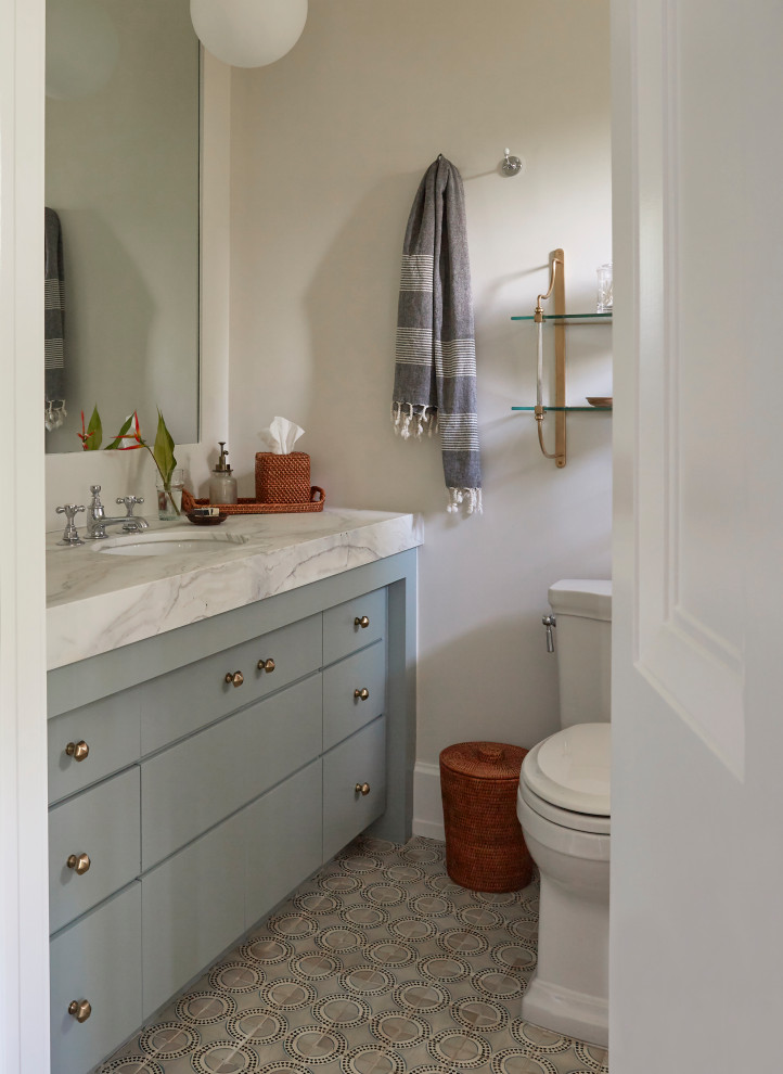 Immagine di una stanza da bagno tropicale con ante lisce, ante blu, pareti bianche, top bianco, un lavabo e mobile bagno incassato