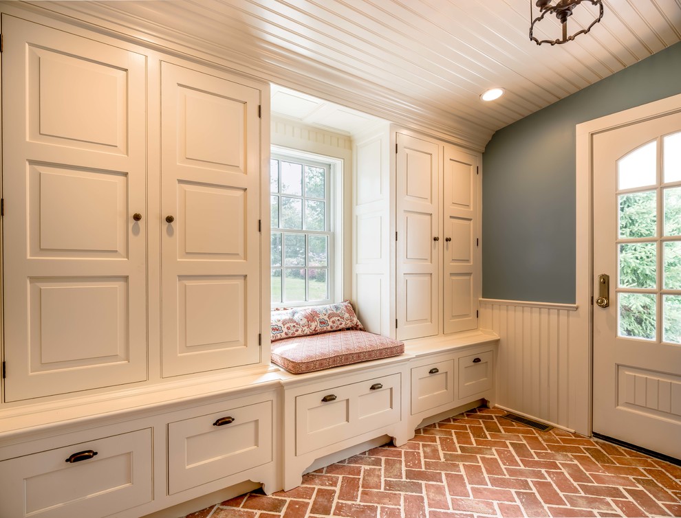 This is an example of a traditional mudroom in Philadelphia with blue walls, brick floors, a single front door, a white front door and red floor.
