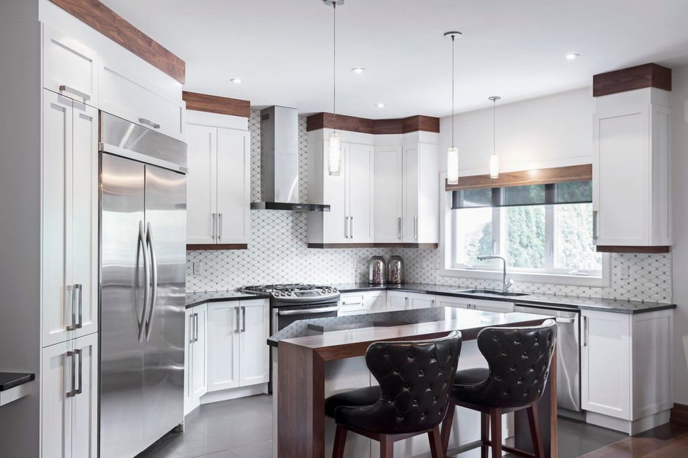Mid-sized eclectic galley eat-in kitchen in Montreal with an undermount sink, shaker cabinets, white cabinets, quartz benchtops, white splashback, marble splashback, stainless steel appliances, ceramic floors, with island, black floor and black benchtop.