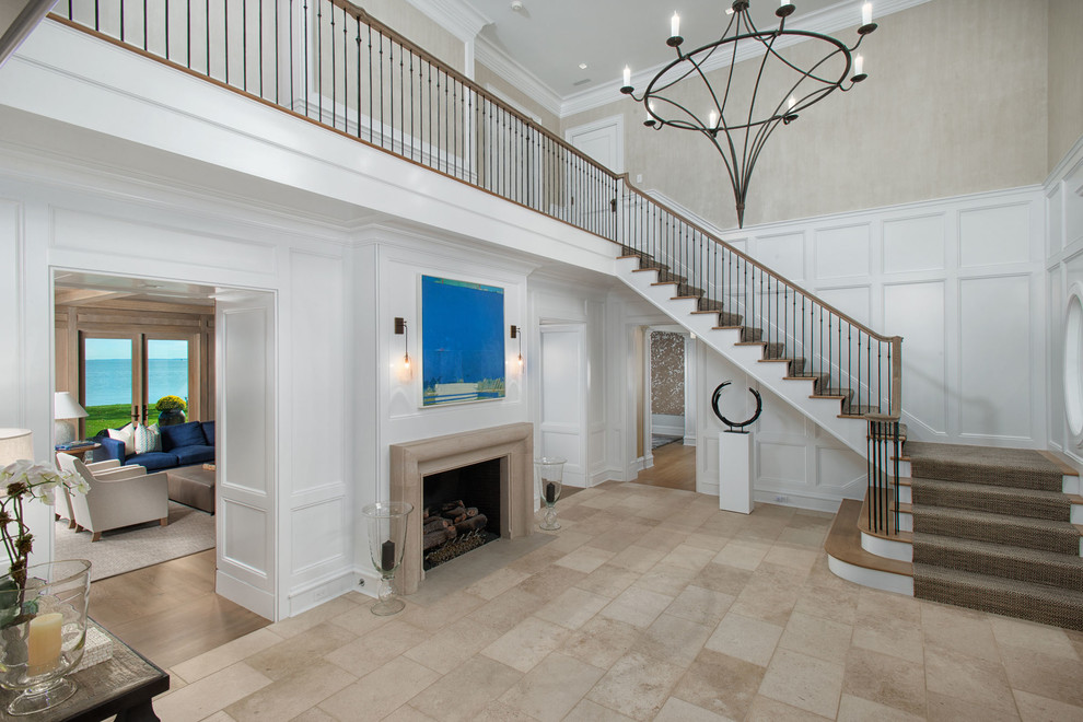 Large beach style foyer in New York with white walls and beige floor.