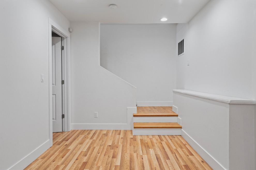Exempel på en mellanstor minimalistisk källare utan fönster, med gröna väggar, laminatgolv, en standard öppen spis, en spiselkrans i tegelsten och beiget golv