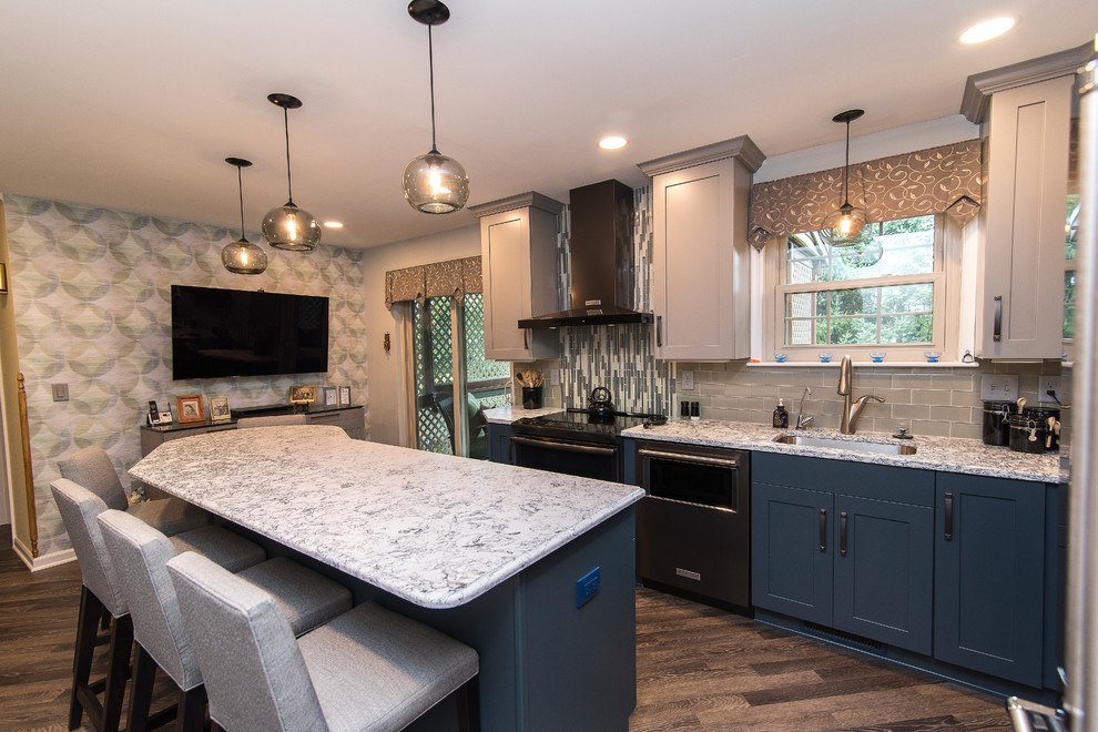 Example of a mid-sized transitional l-shaped brown floor eat-in kitchen design in Baltimore with a single-bowl sink, shaker cabinets, gray cabinets, quartz countertops, gray backsplash, subway tile backsplash, stainless steel appliances, an island and white countertops