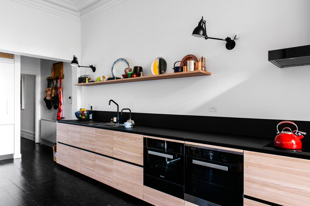 This is an example of a contemporary single-wall kitchen in Melbourne with a double-bowl sink, flat-panel cabinets, black appliances and no island.