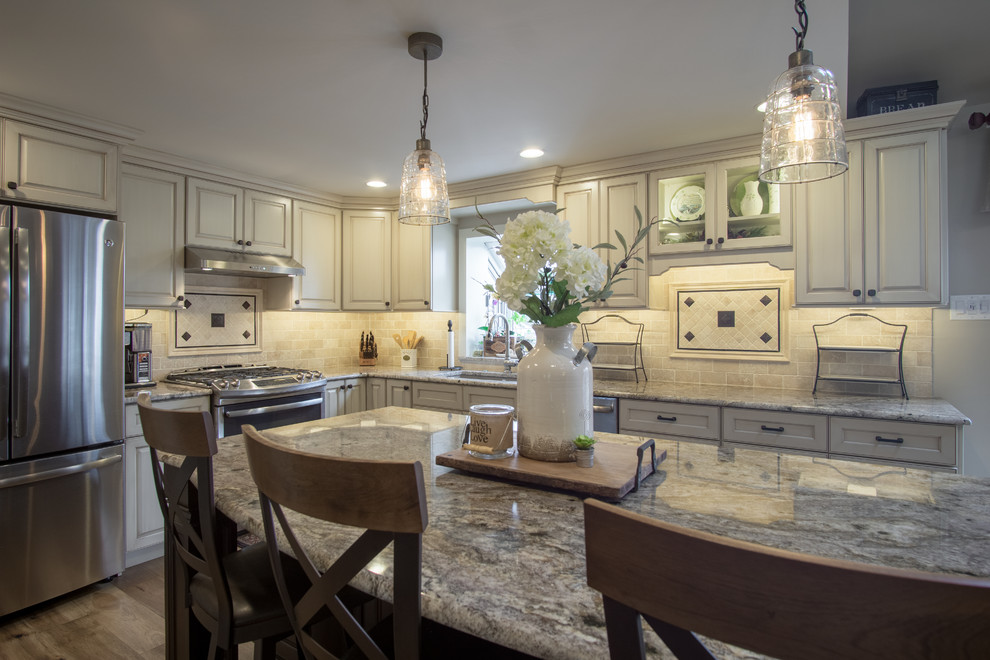 Large transitional l-shaped eat-in kitchen in Philadelphia with an undermount sink, raised-panel cabinets, beige cabinets, granite benchtops, beige splashback, stone tile splashback, stainless steel appliances, medium hardwood floors, with island and brown floor.