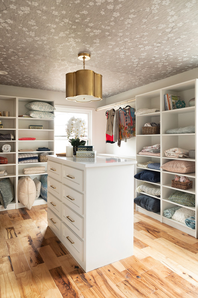 Modelo de armario vestidor unisex con armarios con paneles empotrados, puertas de armario blancas, suelo de madera en tonos medios, suelo marrón y papel pintado