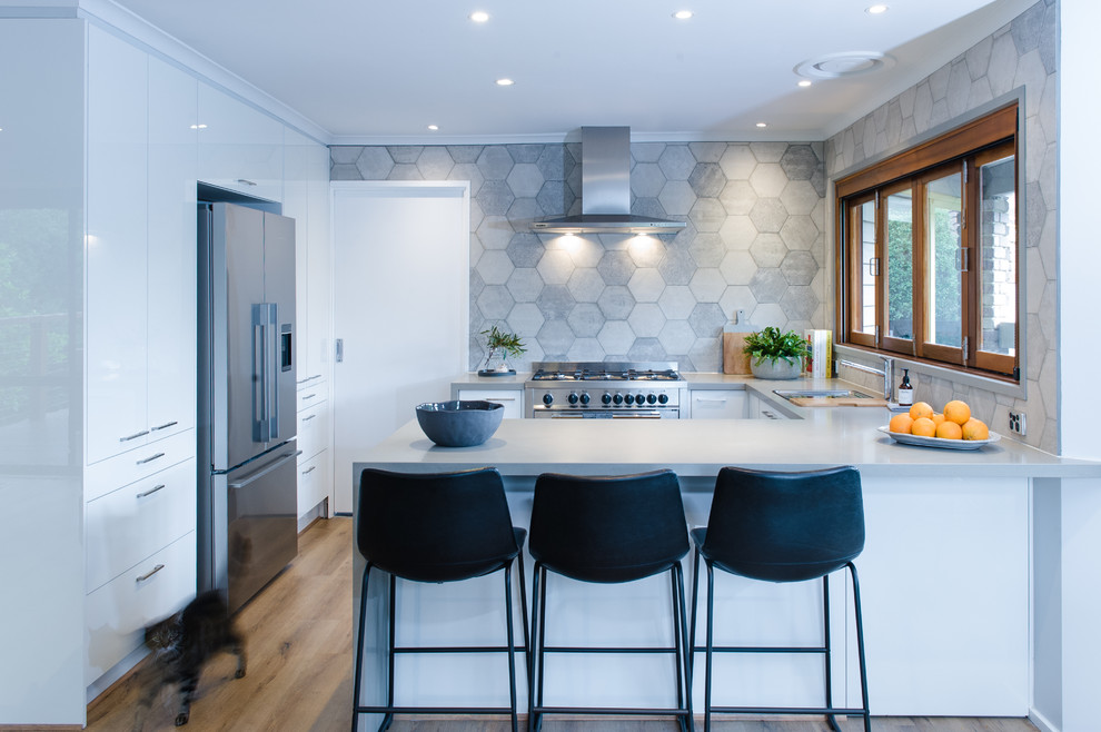 Inspiration for a mid-sized modern u-shaped kitchen in Melbourne with an integrated sink, open cabinets, white cabinets, quartz benchtops, grey splashback, stone tile splashback, stainless steel appliances, medium hardwood floors, with island and grey benchtop.