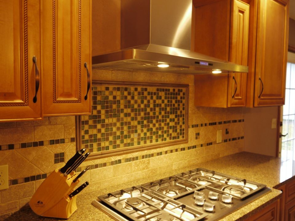Kitchen - large transitional galley kitchen idea in Grand Rapids with an undermount sink, raised-panel cabinets, medium tone wood cabinets, granite countertops, multicolored backsplash, stainless steel appliances and an island