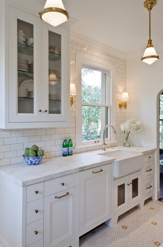 Inspiration for a small traditional separate kitchen in Austin with a farmhouse sink, recessed-panel cabinets, white cabinets, marble benchtops, white splashback, subway tile splashback, no island and porcelain floors.