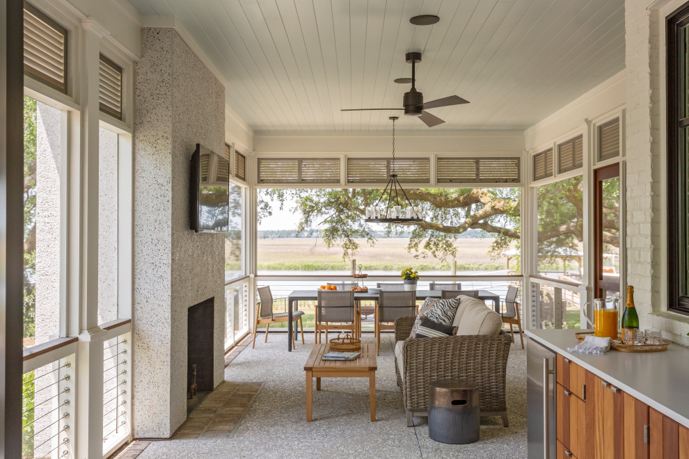 This is an example of a beach style side yard verandah in Charleston with an outdoor kitchen and a roof extension.