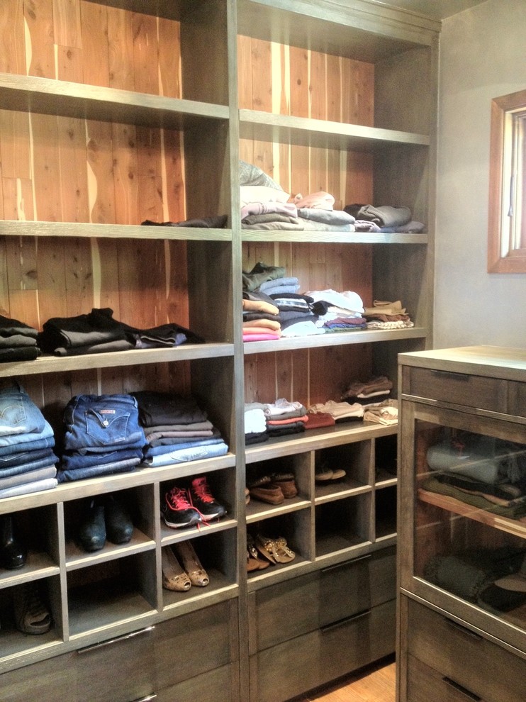 This is an example of a mid-sized industrial women's walk-in wardrobe in Los Angeles with recessed-panel cabinets and dark wood cabinets.