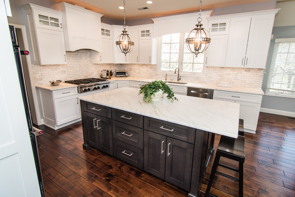This is an example of a large transitional u-shaped kitchen in Philadelphia with a single-bowl sink, flat-panel cabinets, white cabinets, marble benchtops, white splashback, marble splashback, stainless steel appliances, medium hardwood floors, with island and brown floor.