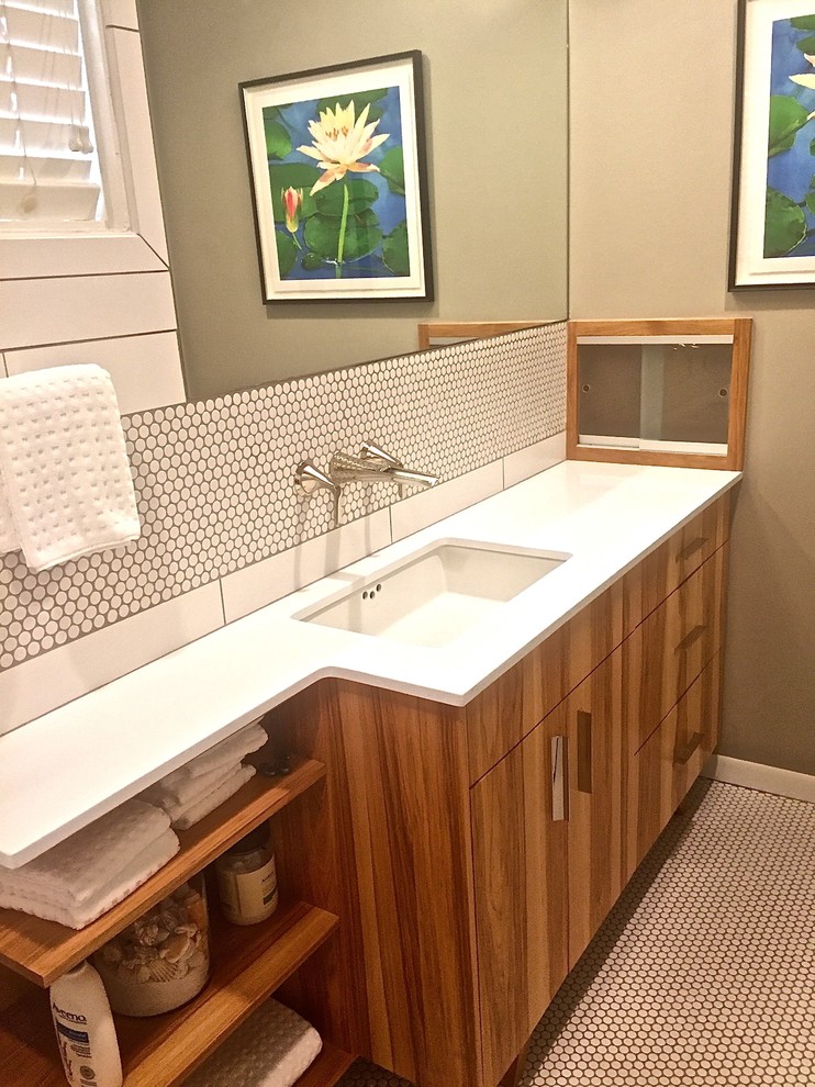 This is an example of a small modern master bathroom in Austin with furniture-like cabinets, medium wood cabinets, a drop-in tub, a shower/bathtub combo, a one-piece toilet, white tile, porcelain tile, beige walls, porcelain floors, an undermount sink and solid surface benchtops.