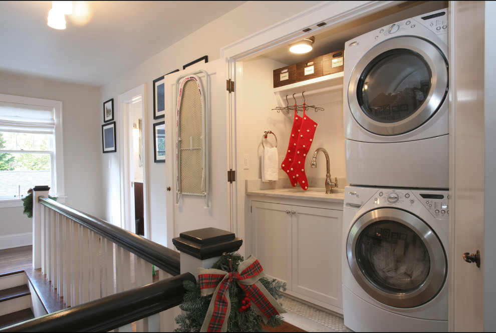 Design ideas for a traditional single-wall laundry cupboard in Portland with an undermount sink, white walls, marble floors, a stacked washer and dryer, white floor, shaker cabinets, white cabinets, marble benchtops and white benchtop.
