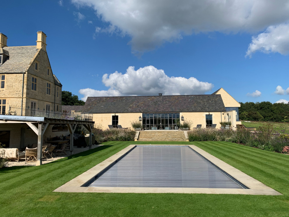 This is an example of a mid-sized country side yard rectangular aboveground pool in Oxfordshire with a pool house.