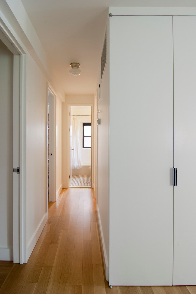 Inspiration for a small modern hallway in New York with white walls, light hardwood floors and beige floor.