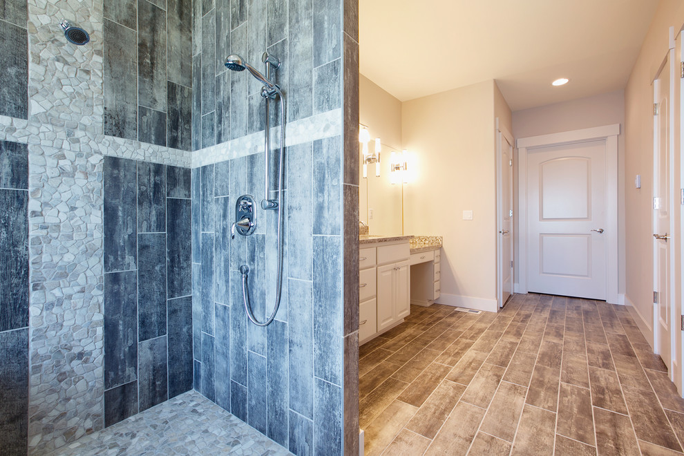 Mid-sized arts and crafts master bathroom in Seattle with an undermount sink, raised-panel cabinets, white cabinets, granite benchtops, a drop-in tub, a double shower, a bidet, gray tile, porcelain tile, white walls and porcelain floors.
