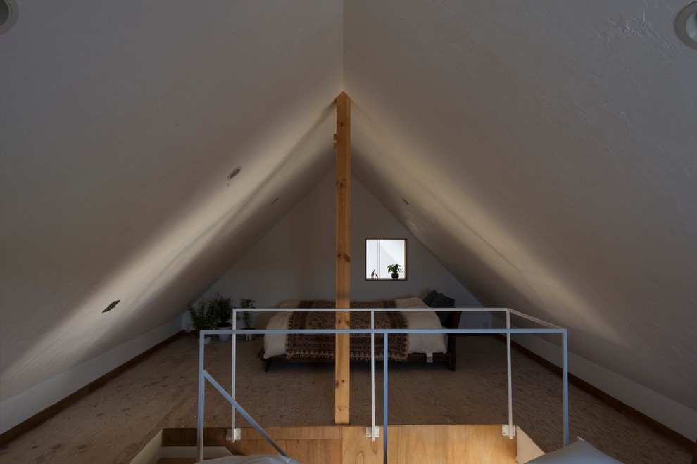 Photo of a mid-sized modern loft-style bedroom in Yokohama with white walls and plywood floors.