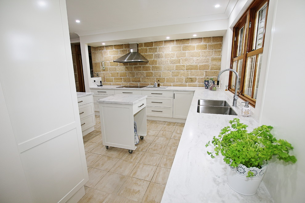 Inspiration for a large traditional u-shaped kitchen pantry in Sydney with a double-bowl sink, shaker cabinets, white cabinets, solid surface benchtops, brown splashback, stone slab splashback, stainless steel appliances, ceramic floors and a peninsula.