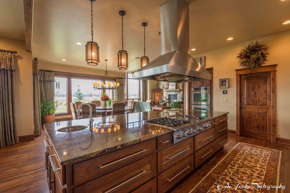 Mid-sized mountain style l-shaped dark wood floor open concept kitchen photo with an undermount sink, shaker cabinets, dark wood cabinets, granite countertops, multicolored backsplash, stone slab backsplash, stainless steel appliances and an island