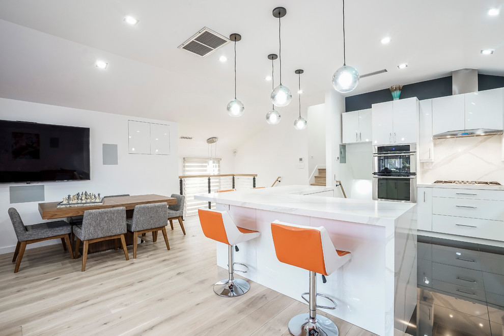 Design ideas for a large contemporary galley eat-in kitchen in New York with an undermount sink, flat-panel cabinets, white cabinets, quartz benchtops, multi-coloured splashback, stone slab splashback, stainless steel appliances, porcelain floors, multiple islands, black floor and white benchtop.