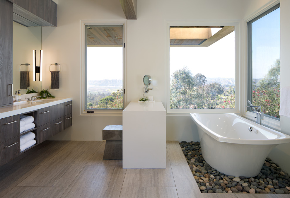 Photo of a large contemporary master bathroom in San Diego with flat-panel cabinets, a freestanding tub, white tile, engineered quartz benchtops, dark wood cabinets, white walls, an undermount sink and beige floor.