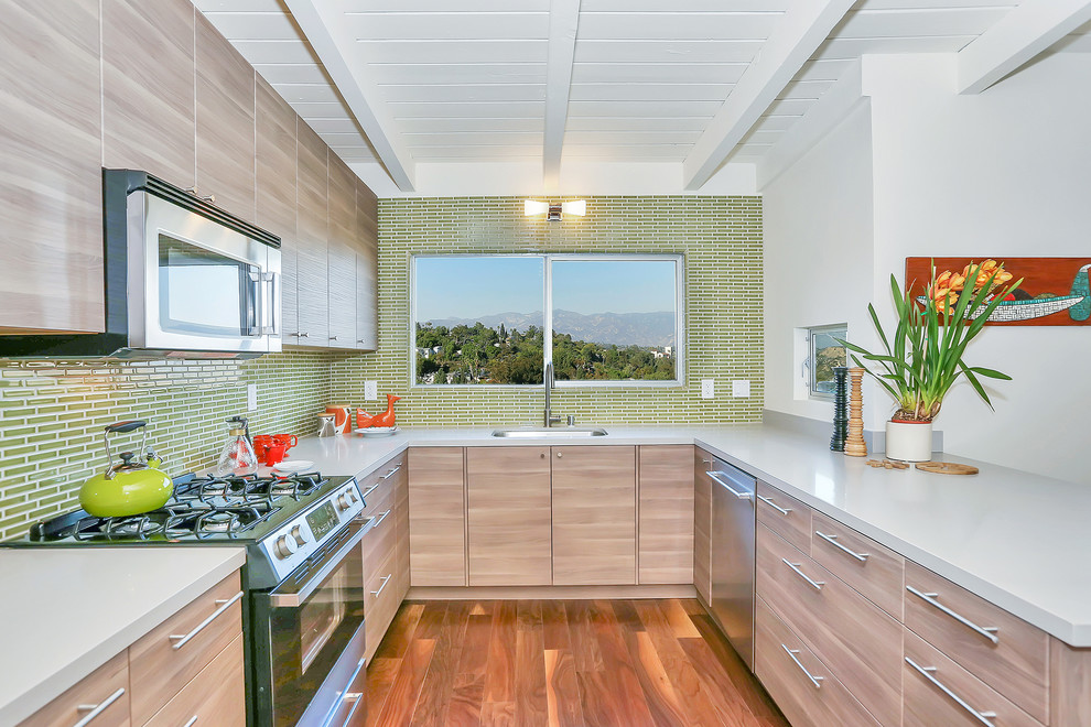 Design ideas for a contemporary u-shaped eat-in kitchen in Los Angeles with a single-bowl sink, flat-panel cabinets, light wood cabinets, green splashback, mosaic tile splashback and stainless steel appliances.
