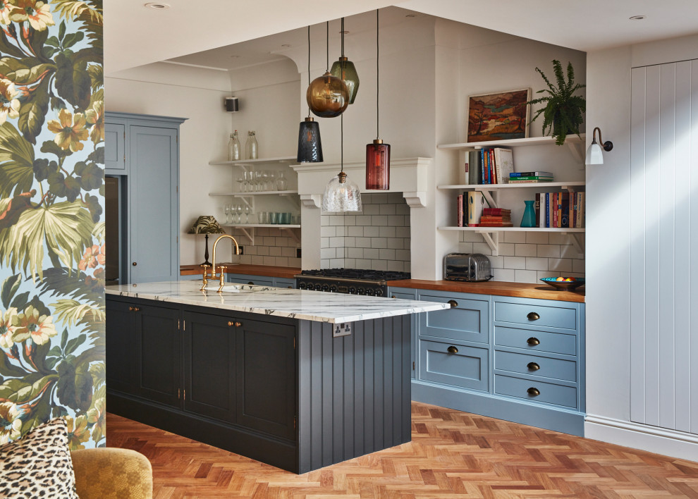 Large elegant eat-in kitchen photo in London with shaker cabinets, blue cabinets, marble countertops and an island