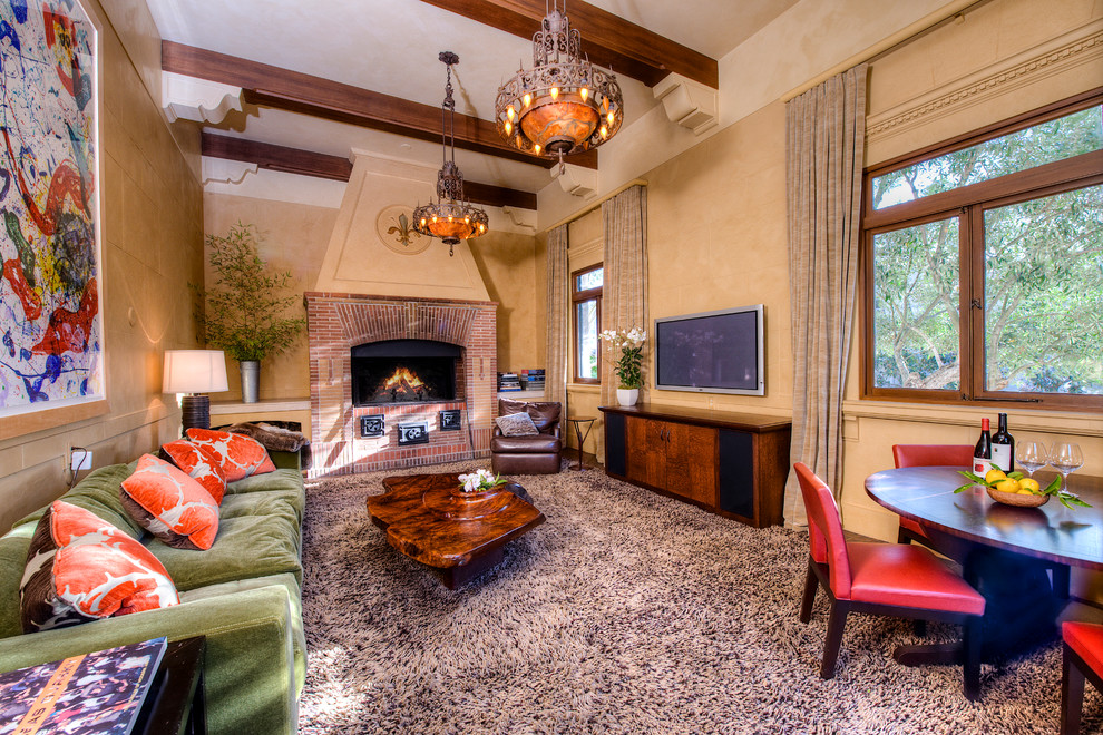Photo of a large mediterranean formal enclosed living room in San Francisco with yellow walls, medium hardwood floors, a standard fireplace, a brick fireplace surround and a wall-mounted tv.
