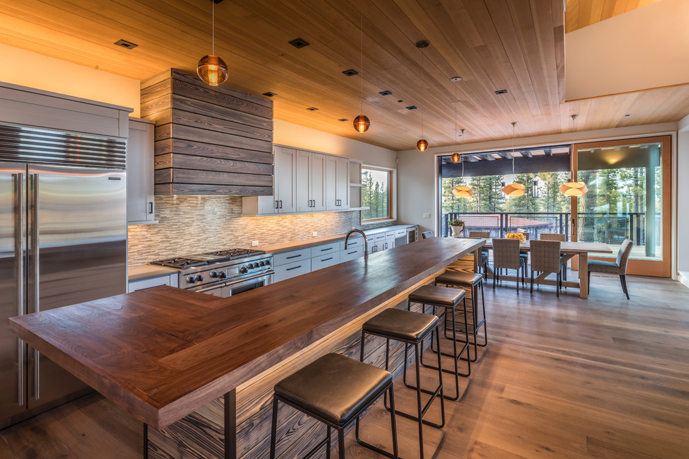 Country eat-in kitchen in Sacramento with shaker cabinets, multi-coloured splashback, matchstick tile splashback, stainless steel appliances, with island and medium hardwood floors.