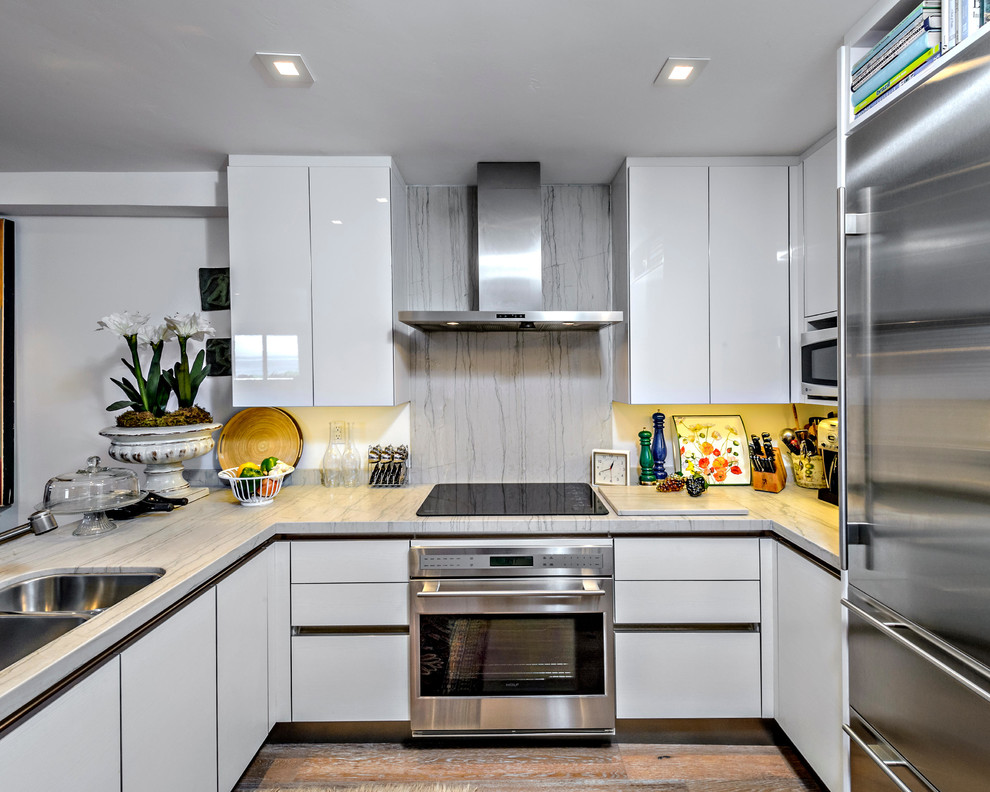 Inspiration for a contemporary u-shaped kitchen in San Diego with a double-bowl sink, flat-panel cabinets, white cabinets, white splashback and stainless steel appliances.