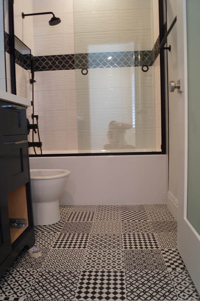 Inspiration for a mid-sized contemporary 3/4 bathroom in Miami with shaker cabinets, black cabinets, an alcove tub, a shower/bathtub combo, a one-piece toilet, black and white tile, porcelain tile, white walls, porcelain floors, a vessel sink, engineered quartz benchtops, multi-coloured floor and a sliding shower screen.