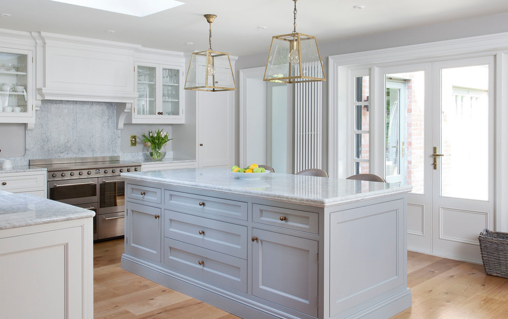 Mid-sized transitional l-shaped open plan kitchen in Dublin with a farmhouse sink, beaded inset cabinets, grey cabinets, marble benchtops, grey splashback, marble splashback, stainless steel appliances, light hardwood floors, with island and brown floor.