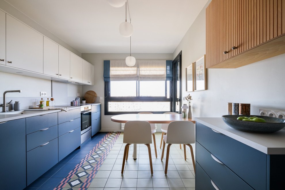 Inspiration pour une cuisine linéaire design de taille moyenne avec un placard à porte plane, des portes de placard bleues, carreaux de ciment au sol, un sol multicolore, un plan de travail gris et machine à laver.