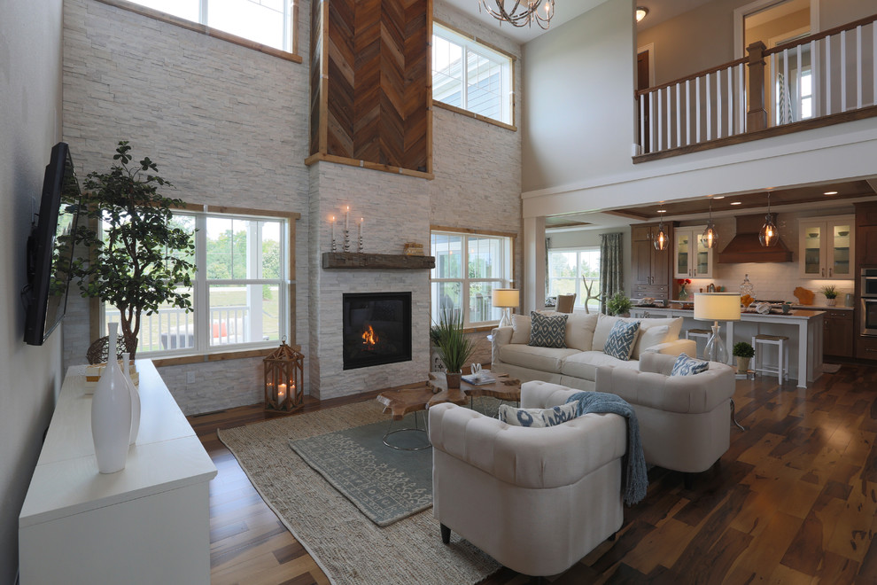 Photo of a country open concept family room in Milwaukee with grey walls, light hardwood floors, a standard fireplace, a stone fireplace surround and a wall-mounted tv.