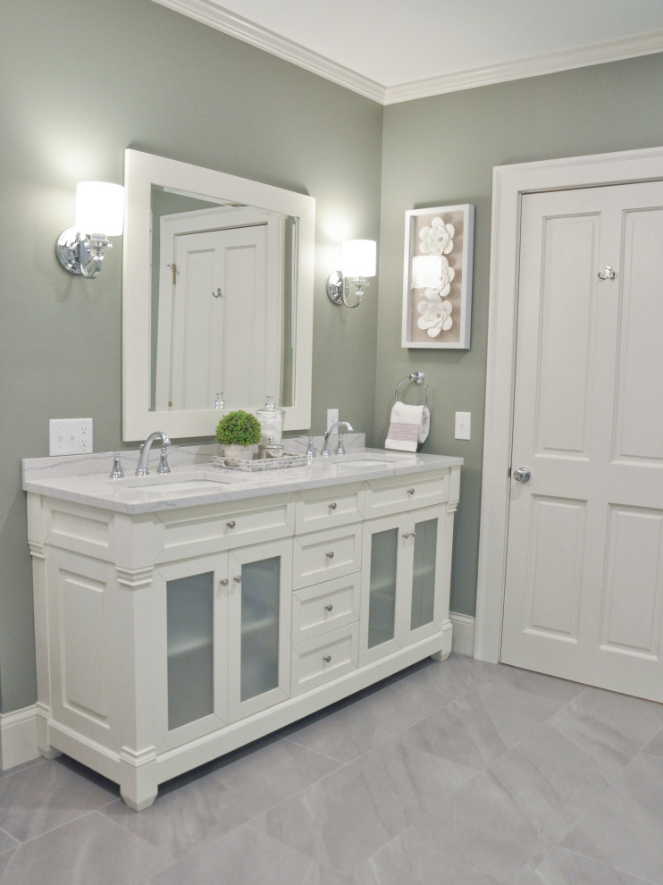 This is an example of a mid-sized transitional master bathroom in Other with glass-front cabinets, white cabinets, a freestanding tub, a curbless shower, a wall-mount toilet, white tile, subway tile, green walls, porcelain floors, an undermount sink, engineered quartz benchtops, grey floor, a hinged shower door and white benchtops.