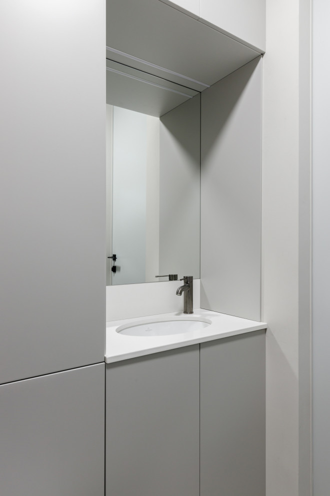 Example of a small trendy porcelain tile and white floor powder room design in Moscow with flat-panel cabinets, gray cabinets, white walls, a wall-mount toilet, an undermount sink, quartz countertops, white countertops and a built-in vanity