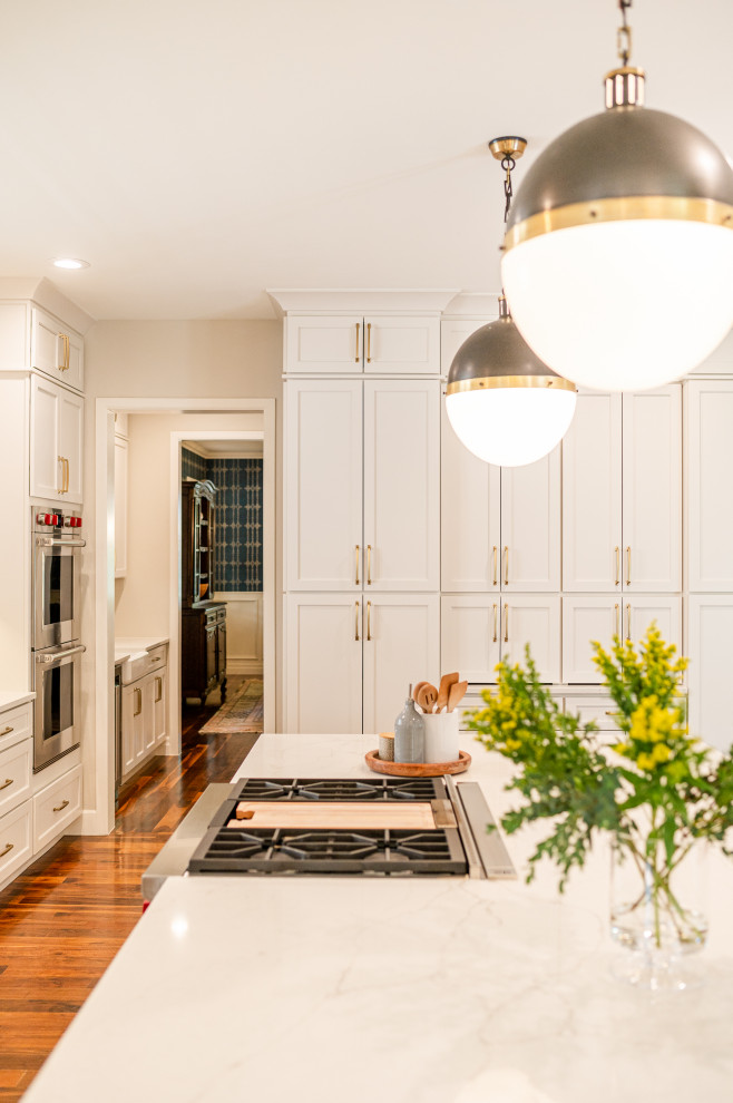 Example of a large transitional l-shaped dark wood floor and brown floor open concept kitchen design in Denver with a farmhouse sink, shaker cabinets, beige cabinets, quartz countertops, beige backsplash, ceramic backsplash, stainless steel appliances, an island and white countertops