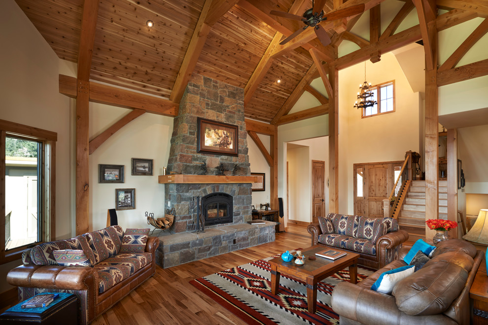 Design ideas for a country living room in Denver with beige walls, dark hardwood floors, a standard fireplace and a stone fireplace surround.