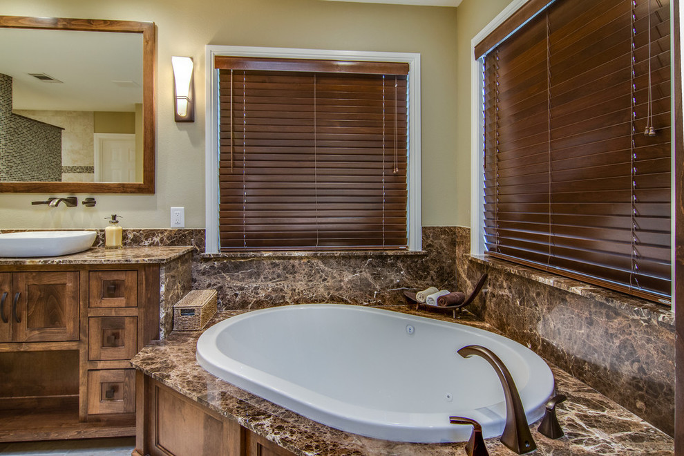 This is an example of a mid-sized traditional master bathroom in Dallas with a vessel sink, shaker cabinets, medium wood cabinets, a drop-in tub, multi-coloured tile and beige walls.
