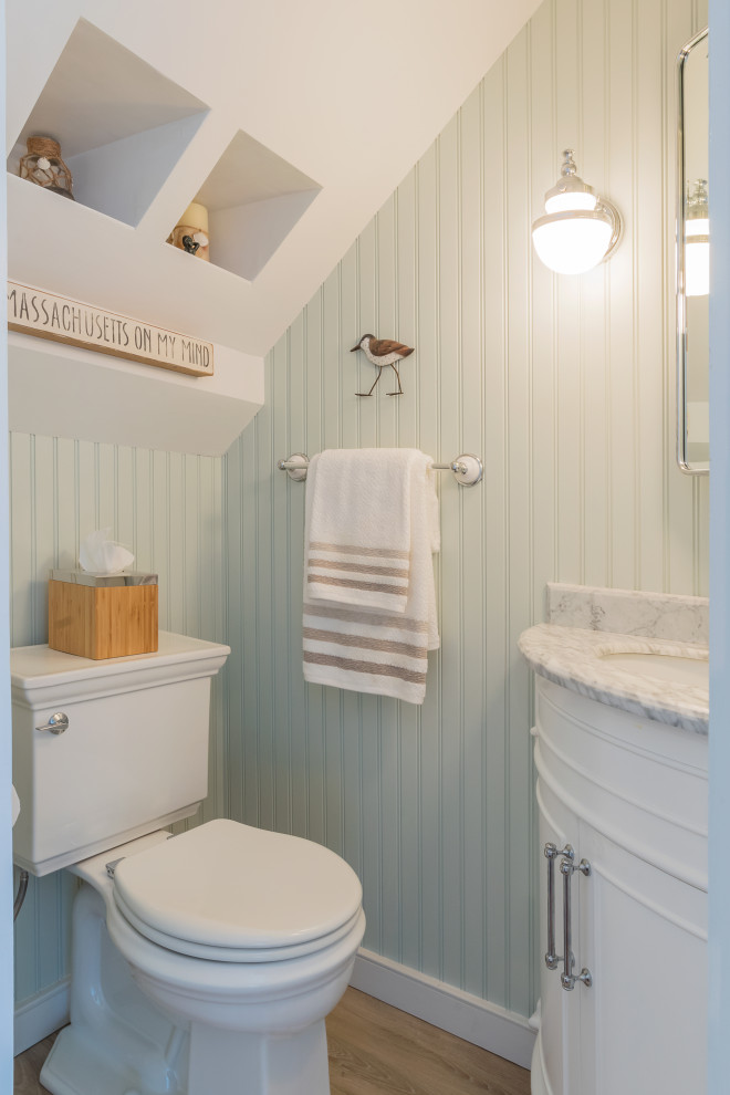 This is an example of a small beach style 3/4 bathroom in Boston with beaded inset cabinets, white cabinets, a one-piece toilet, blue walls, light hardwood floors, an undermount sink, quartzite benchtops, brown floor, a single vanity, a built-in vanity and wood walls.