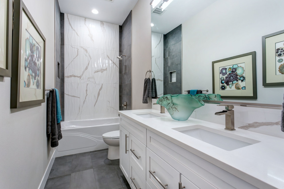 This is an example of a mid-sized transitional bathroom in Seattle with shaker cabinets, white cabinets, an alcove tub, a shower/bathtub combo, a two-piece toilet, white tile, porcelain tile, an undermount sink, engineered quartz benchtops, a shower curtain and white benchtops.
