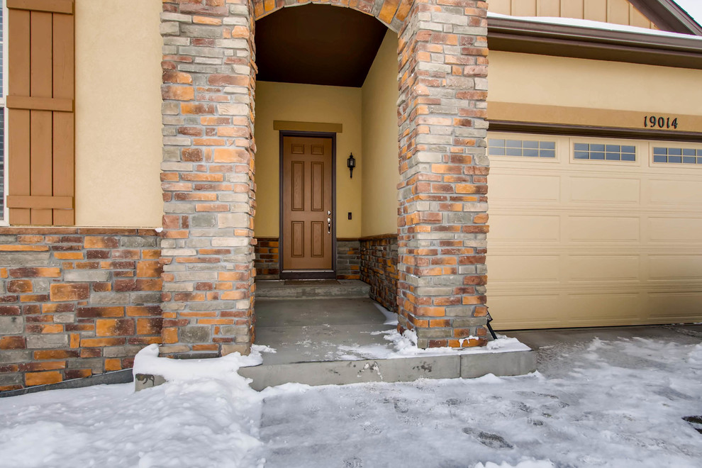 Example of a mid-sized classic concrete floor and gray floor front door design in Denver with no fireplace, yellow walls and a medium wood front door