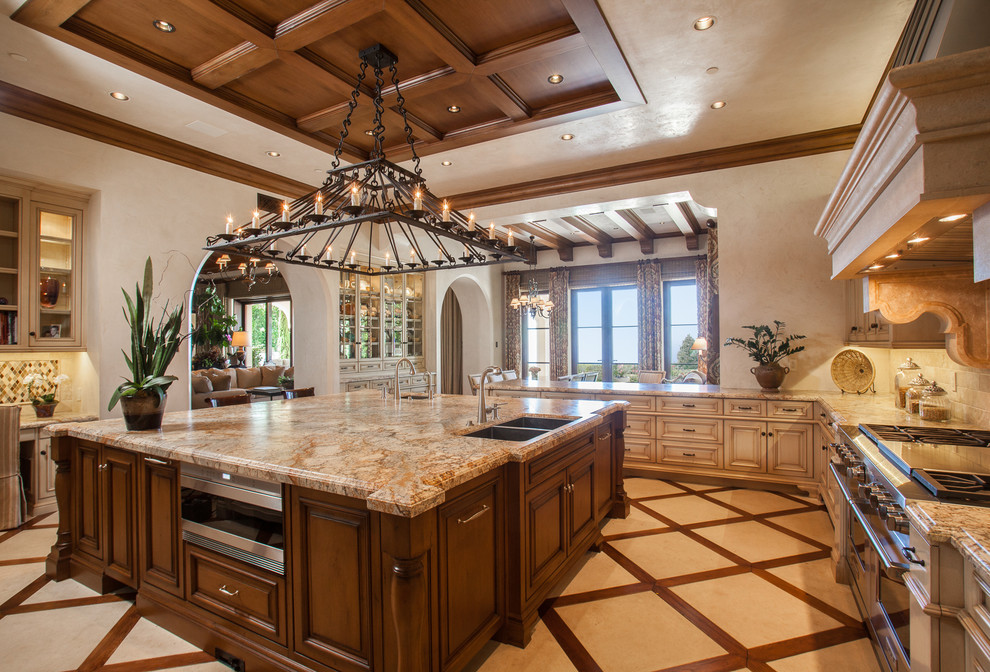 Photo of a large mediterranean l-shaped separate kitchen in Orange County with raised-panel cabinets, beige cabinets, with island, a double-bowl sink, beige splashback, stainless steel appliances, multi-coloured floor and beige benchtop.