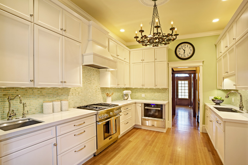Inspiration for a traditional separate kitchen in San Francisco with an undermount sink, recessed-panel cabinets, white cabinets, quartz benchtops, green splashback and stainless steel appliances.