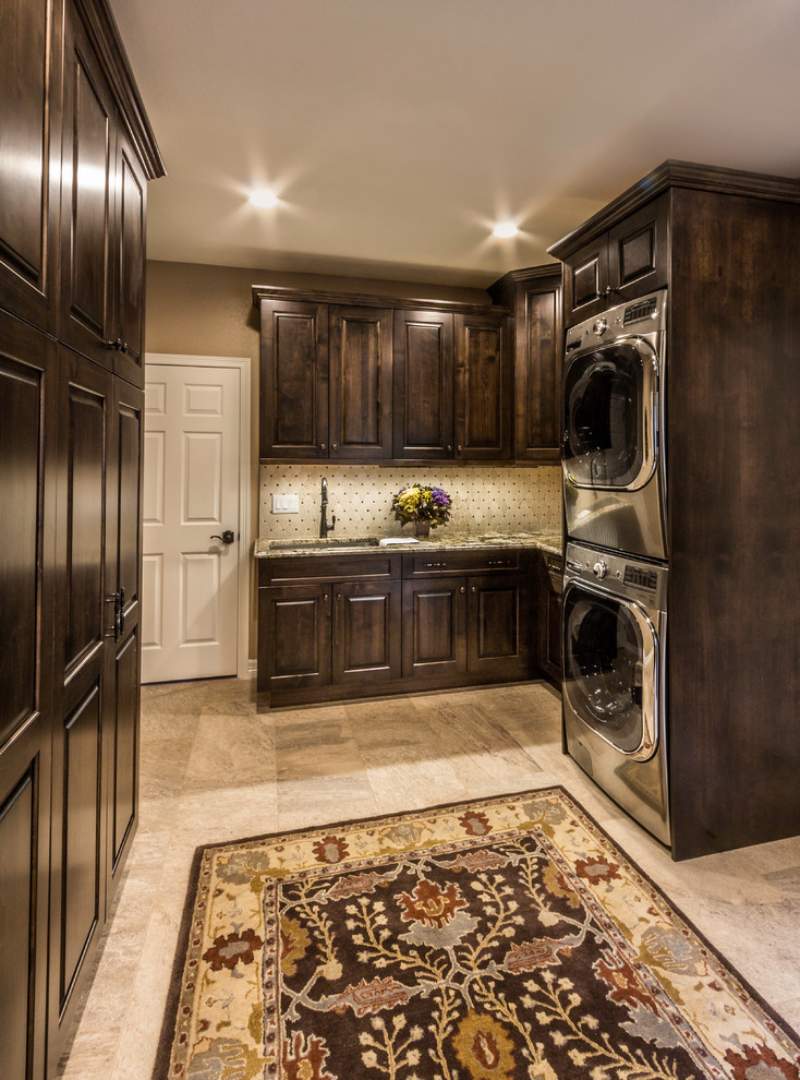 Design ideas for a large traditional utility room in Denver with an undermount sink, dark wood cabinets, granite benchtops, porcelain floors and a stacked washer and dryer.